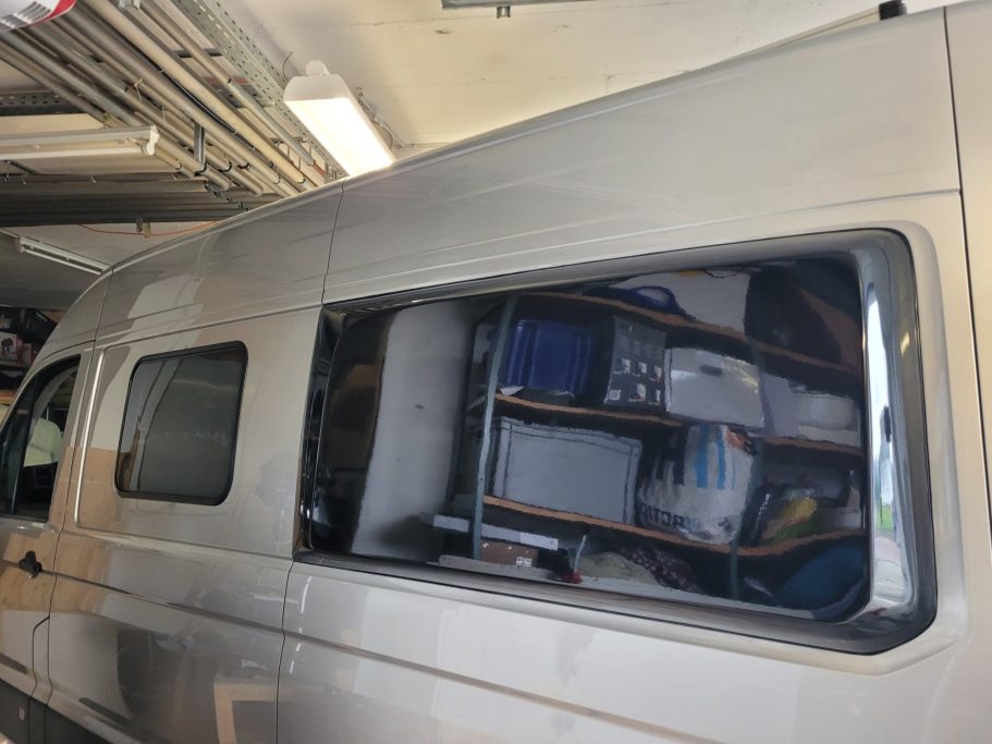 Silberner Van mit geöffnetem Fenster, innen sind Regale mit verschiedenen Gegenständen sichtbar.